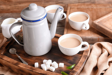 Composition of aromatic tea with milk on wooden board