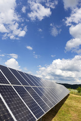 Solar Power Station on the spring Meadow with cloudy Sky 