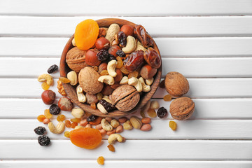 Plate with different nuts and dried fruits on wooden table, top view