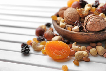 Plate with different nuts and dried fruits on wooden table