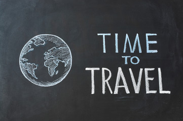 Chalk inscription "Time to travel" on a blackboard.