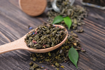 Spoon with green tea leaves on wooden background