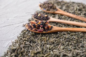 Spoon and different types of dry tea on table