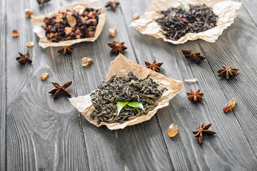 Different types of dry tea leaves on wooden background