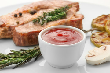 Bowl with barbecue sauce and grilled meat, closeup