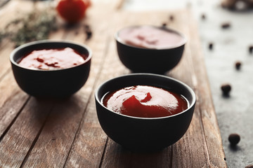 Delicious barbecue sauces in bowls on wooden board