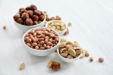 Bowls with different kinds of nuts on light background