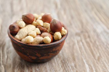 Bowl with mix of nuts on wooden background