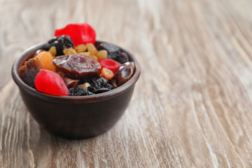 Bowl with mix of dried fruits and berries on wooden background