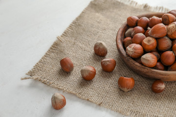 Plate with tasty hazelnuts on table