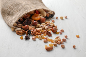 Sackcloth bag with mix of nuts and dried fruits on light background