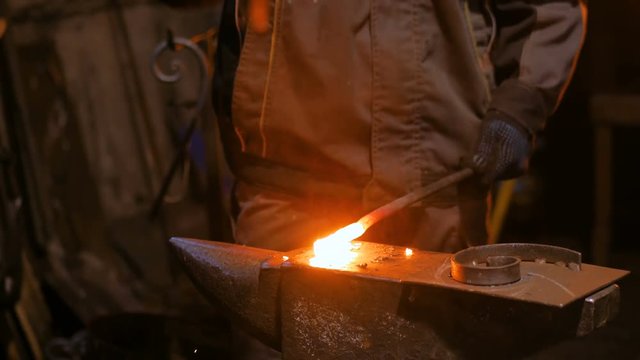 Professional blacksmith forging molten metal on anvil at smithy, workshop. Handmade, craftsmanship and blacksmithing concept