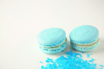 Tasty macarons with blue sugar on white background