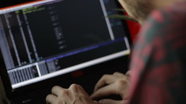 Close up of a programmer writing codes in front of a notebook monitor.