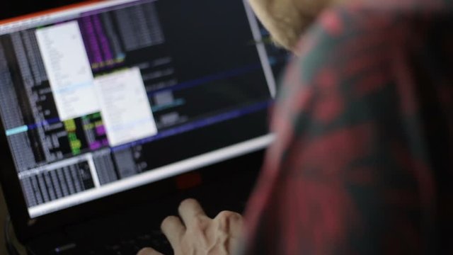 Close up of a hacker coding in front of a notebook monitor.