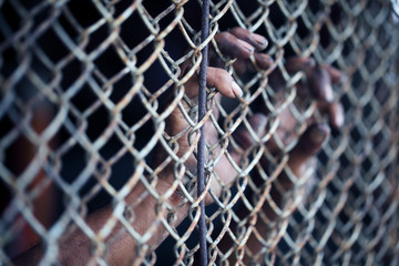 hands of prisoner in jail background.
