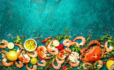 Frische rohe Meeresfrüchte - Garnelen und Krabben mit Kräutern und Gewürzen auf türkisfarbenem Hintergrund. Platz kopieren © lblinova