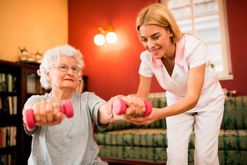 Fototapeta premium Smilinig positive senior woman enjoy in exercise with nurse
