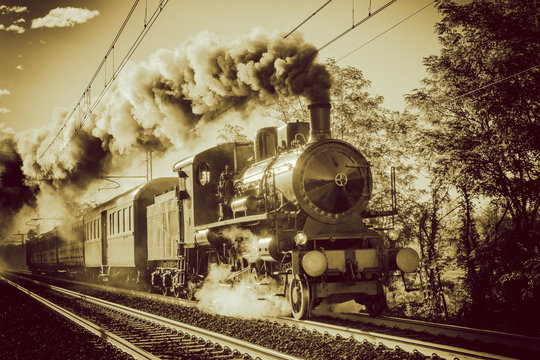 Steam train running on rails, vintage retro film photo filter applied.