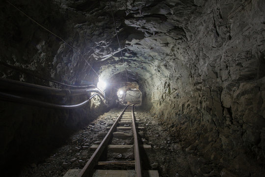 Underground glod ore mine shaft tunnel gallery with railway rails