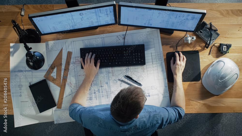 Poster top view of architectural engineer working on his blueprints, holding tablet computer, using desktop
