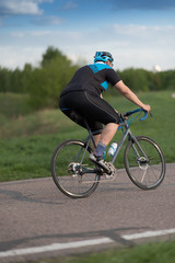 Cyclist man riding road sport bike in sunny day on a mountain road