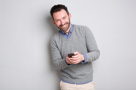 businessman holding cellphone against gray background