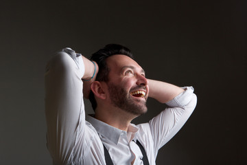 happy man with beard laughing with hands behind head