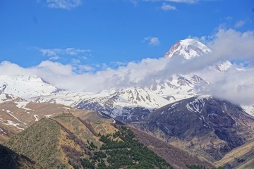 Fototapeta premium View of the glacier peak Kazbek in the clouds and Gergeti Trinity Church, Caucasus, Kazbegi District, Georgia (Europe) 
