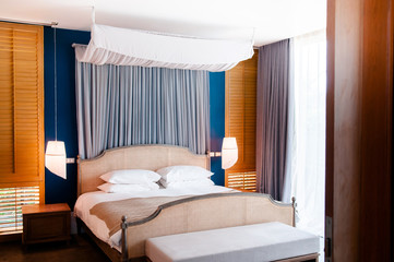 Colonial style bedroom wooden bed with curtain, pillows and lamp