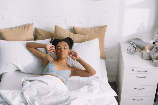 beautiful african american girl waking up in bed in morning