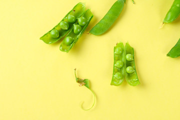 Peas, pods, leaves and pea flowers on a light pastel background. Floral layout.