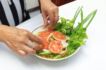 woman perpares dish of thai salad on white table