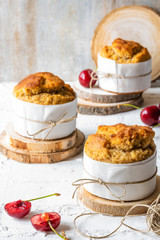 Three muffins with cherries on rustic background