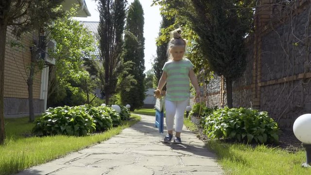 Adorable little girl walking at backyard with basket of flowers and toys