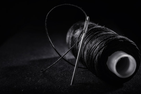 Needle with thread, thimble, bobbin with black thread and scissors