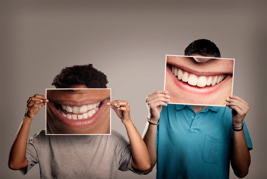 happy couple holding a picture of a mouth smiling on a gray background