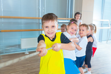 Children and recreation, group of happy multiethnic school kids playing tug-of-war with rope in gym