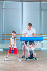 Group of children doing kids gymnastics in gym with teacher. Happy sporty children in gym. foam roller