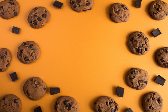 Top view chocolate cookies  and pieces  of chocolate on the light brown  background
