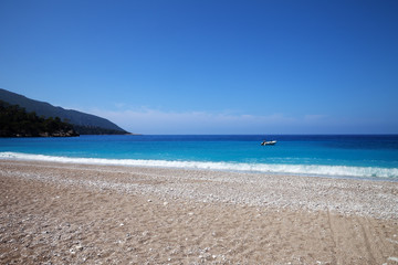 Sand beach with pebble stones and beautiful blue sea