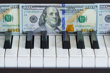 One hundred dollar bills in front of piano keys (concept)