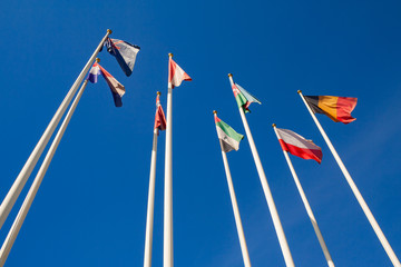 Obraz premium Bottom view of a flags of different countries against a clear blue sky