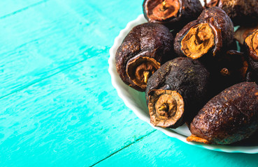 Dried persimmon - healthy raw dessert in a plate on a blue wooden background