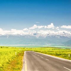 Road running through the countryside overlooking snow-capped mountains - the Caucasian Range