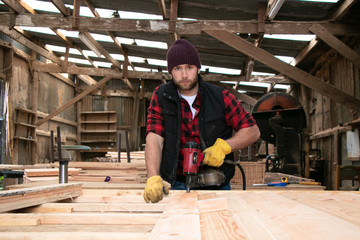 Fototapeta premium Handsome male wood worker, carpenter building fence in wood mill