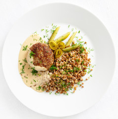 poultry meatball with buckwheat, pickled cucumber, and gravy sauce sprinkled with dill