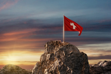 Wehende Schweizer Fahne auf Bergspitze im wunderschönen Abendrot - obrazy, fototapety, plakaty