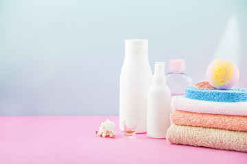 Obraz na płótnie Canvas bathroom accessories - towels and shampoos,bath foam, cream on a light, bright blue and pink background The concept of caring for yourself, your body. Place for copy space
