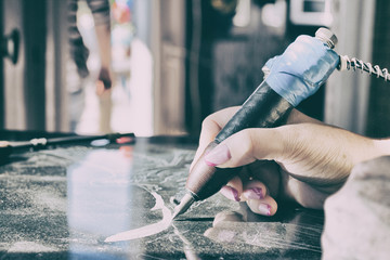 Description.Girl engraves on granite